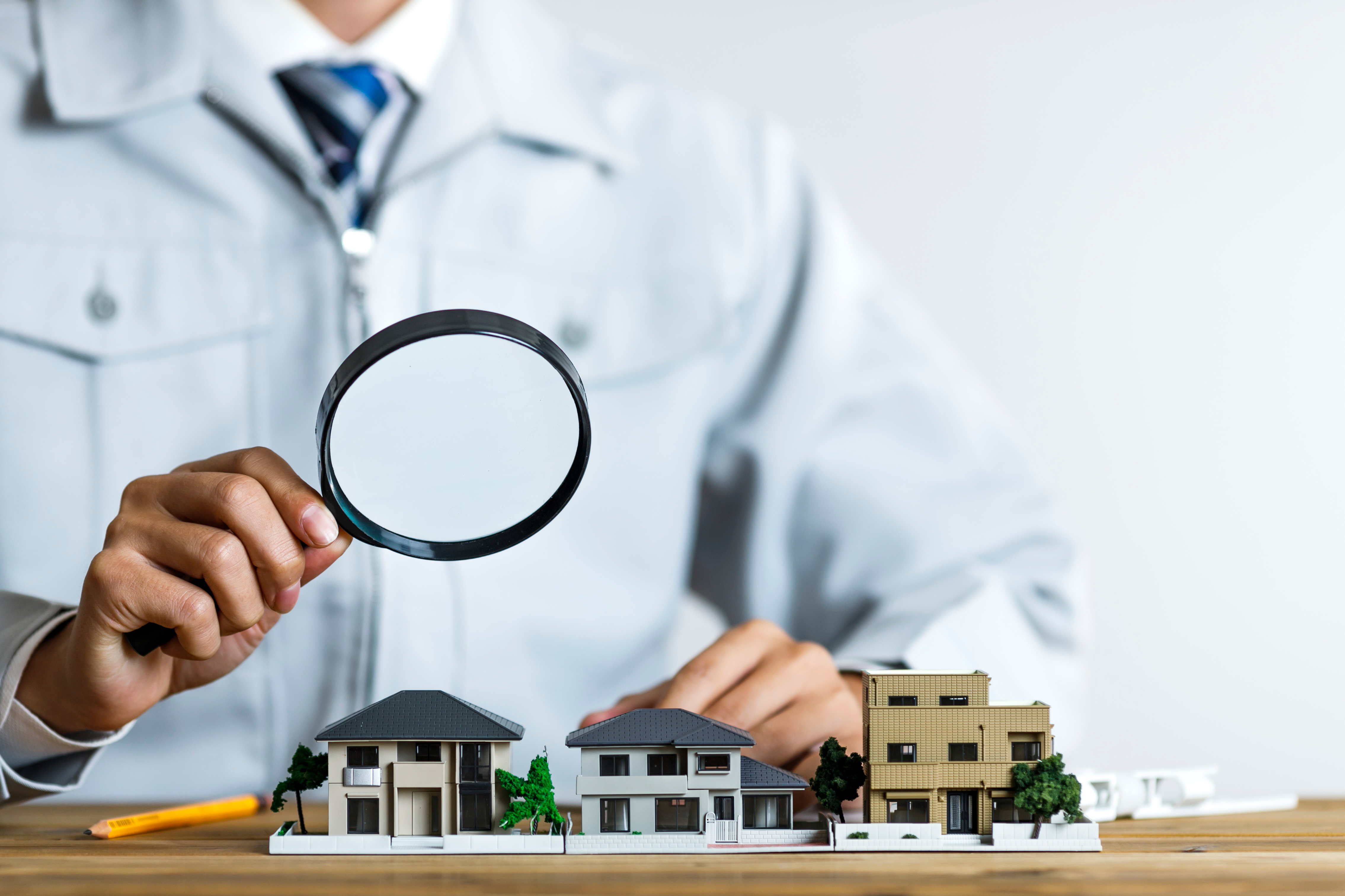 住宅模型をルーペで覗く作業服の男性